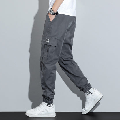 Person wearing gray cargo pants and white sneakers on a plain background