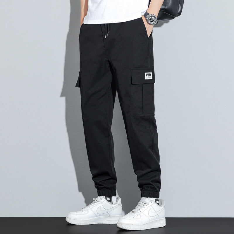 Person wearing black cargo pants with a gray background