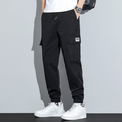 Person wearing black cargo pants with a gray background